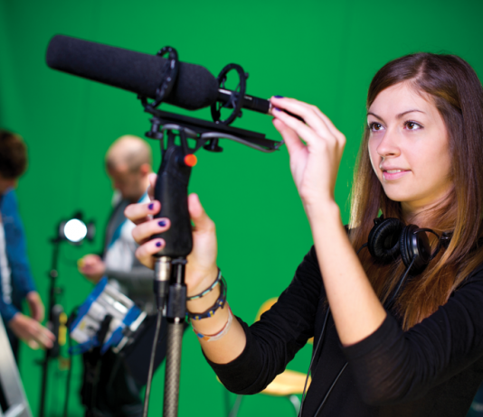 Shot of a young woman putting a shotgun mic into a boom holder.